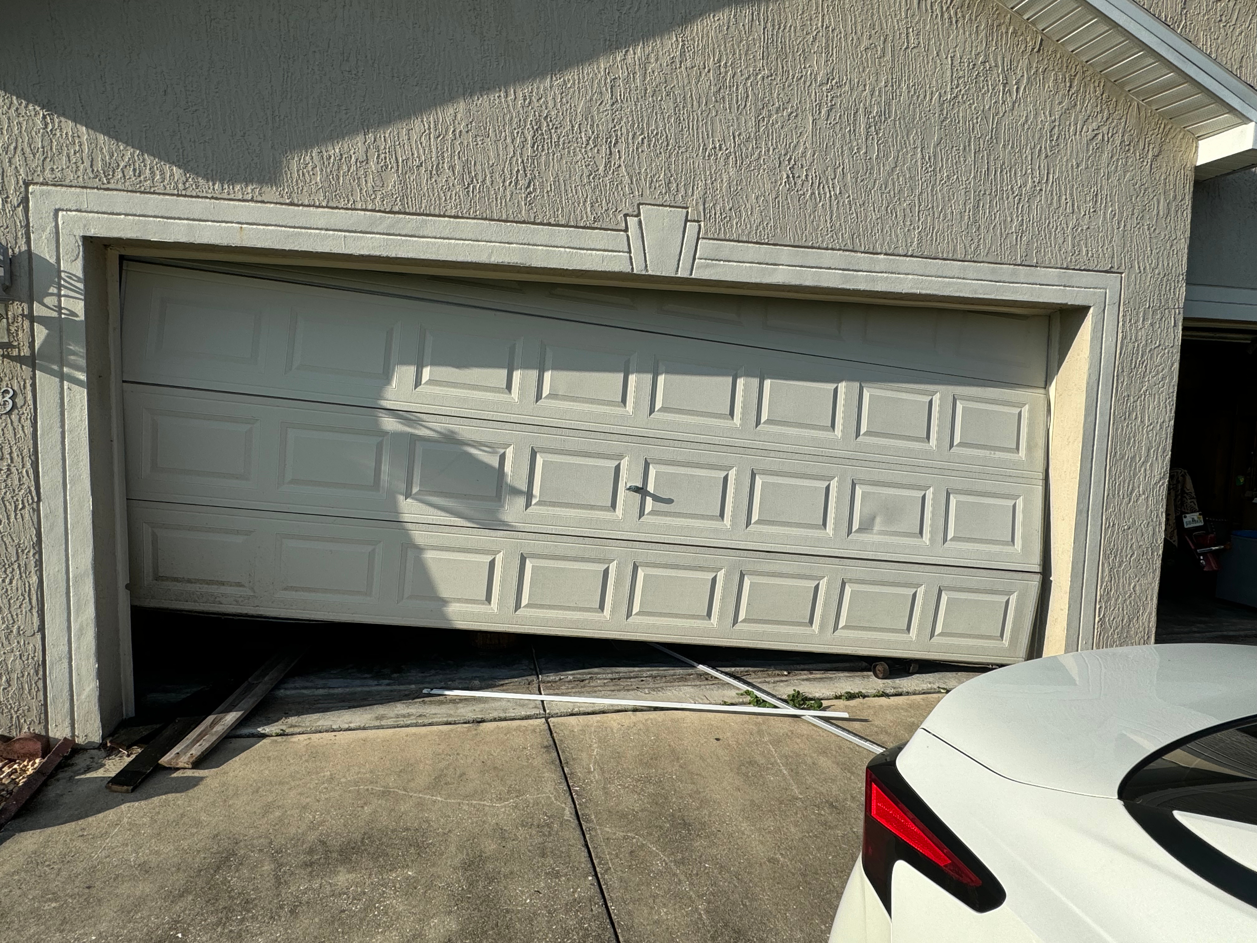 Crooked and broken residential garage door off track at Ocala home