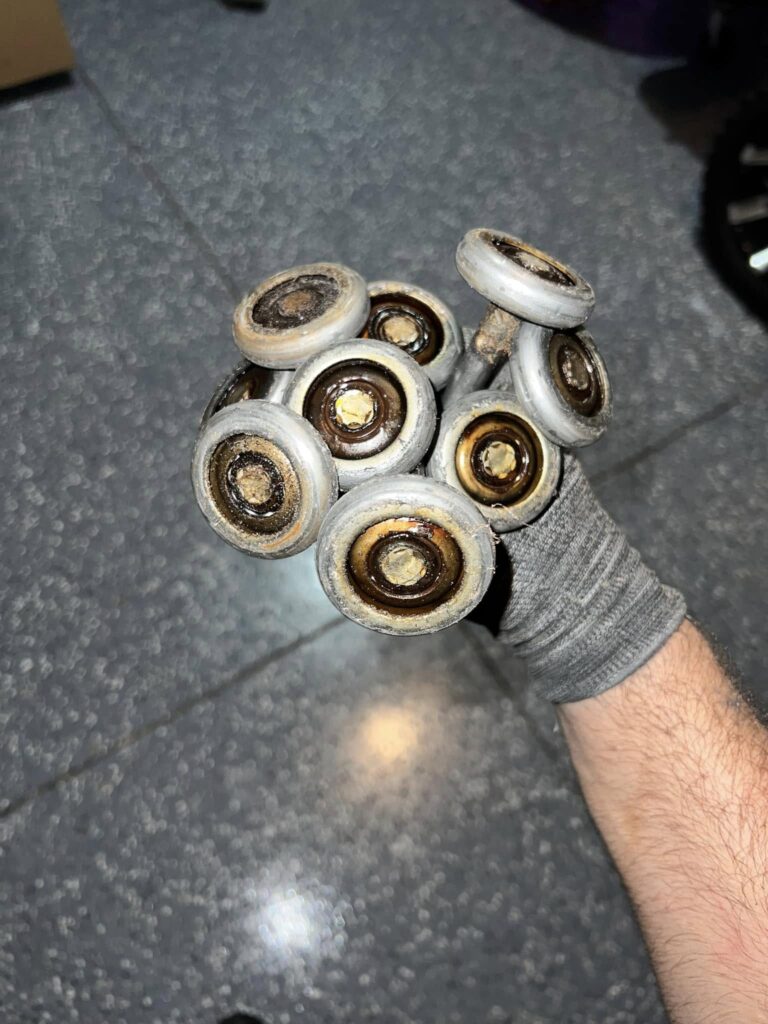 Worn garage door rollers removed during professional garage door repair service