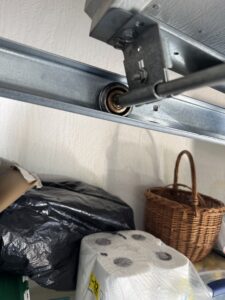 Garage door roller inside metal track during inspection for replacement